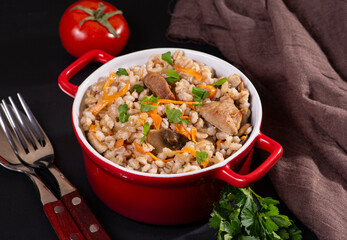 Easy bulgur pilaf (pilavi) with tomatoes in a ceramic bowl on a dark background close-up.