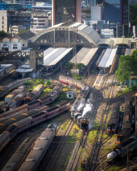 A ancient locomotive train is travelling out from railway station. Taken picture at Bangkok railway station.