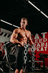 Fototapeta na wymiar Succesful sportsman shows his body and results of trainings and posing with chains in special grung background.