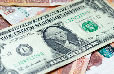 A banknote with a face value of 1 dollar lies on Russian money. The concept of finance, investment, savings and cash.