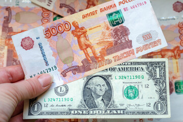 Banknotes of 5000 rubles and 1 dollar in a woman's hand against the background of Russian money. The concept of finance, investment, savings and cash.