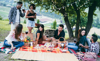 Happy friends having fun drinking wine at picnic dinner outdoor - Focus on center man face