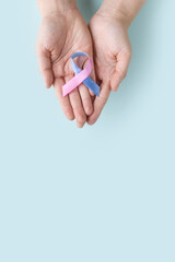 World Thyroid Day. Adult hands holding Thyroid cancer awareness ribbon in Teal Pink Blue. Problems with thyroid. Polycystic disease. World cancer day. vertically photo with copy space.