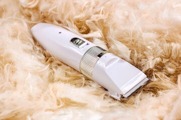White pet hair trimmer of clipper machine for cat and dog grooming on light cutting fur background.