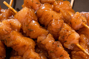close up of several raw chicken skewers on a plate