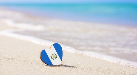 Flag of Guatemala in the shape of a heart on a sandy beach. The concept of the best vacation in...