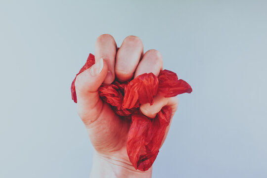 Hand Squeezing A Red Made Of Plastic Package In A Fist, Human And Ecology Concept 