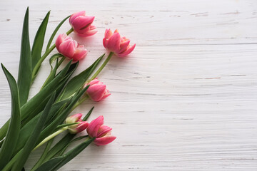 Bouquet of pink tulips on a white wooden background. Place for text