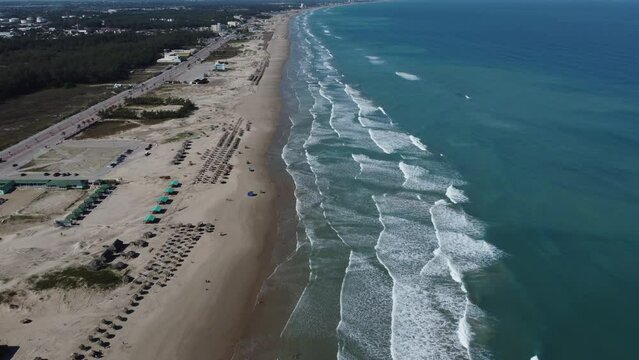 A wide footage of the beaches in Tampico with the ocean waves hitting the sand and birds flying up in the sky