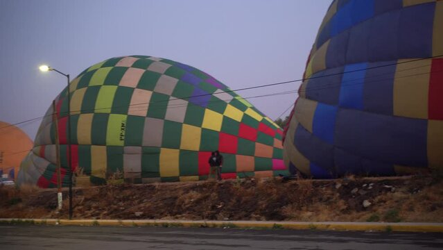 A lot of hot air balloon laying on the ground early in the morning ready to fly over the pyramids in Teotihuacan