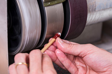 craftsman rolling a wooden stick under a metal lap with the white gemstone on it during cutting...