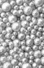 Beautiful background with mother-of-pearl gray pearls, top view. Abstract texture for festive backgrounds. Shiny surface of Christmas decorations. Gems close-up. Silver bright background.