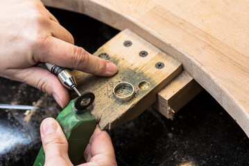 Polisher hands using a green polishing compound on the white metal ring.