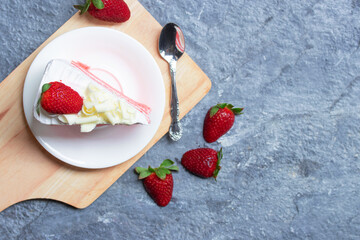 Delicious homemade strawberry cake and fresh milk cream in white dish on gray stone table rustic style. Top view with copy space.