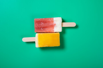 top view two vibrant color popsicles on green background
