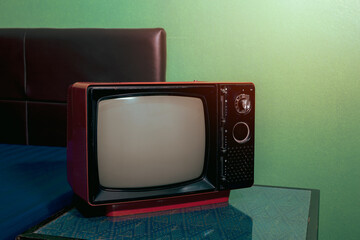 Retro old TV with blank screen in bedroom in front of green wall background.