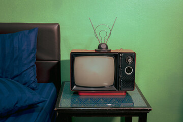 Red retro old TV with antenna on table in the bedroom.