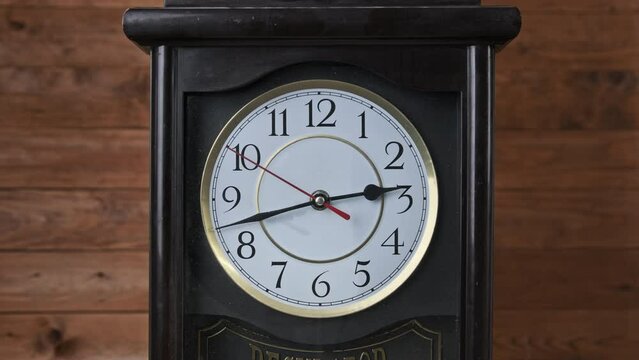 Vintage Wall Clock with Moving Second Hand on Wooden Background. Old Retro clock with a white circular dial. Old-fashioned antique clock. Arrow clock with second, minute, and hour hand.