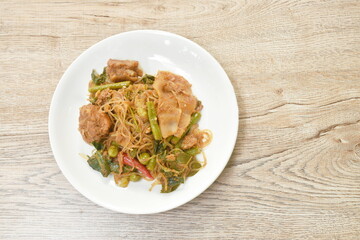 spicy stir fried glass noodles with pickled bamboo and mixed vegetable couple pork Thai northern style food called Pad Hor on plate