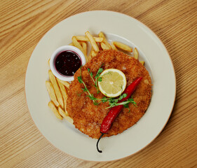 schnitzel with french fries, sauce and pepper