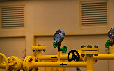 Przemysł gazowy , przepompownia gazu ziemnego ( metan) , żółte rury , zawory pokrętła i manometry .