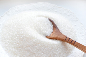 White sugar in a wooden spoon in bulk and cubes