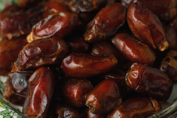Dried dates in a green vintage plate on a brown textile background. Rustic style