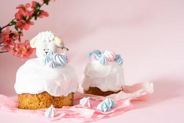 Easter cake with white icing and blue meringues Easter decorative lamb on a pink background with spring cherry blossoms and copy space. Easter Ukraine orthodox sweet bread. Easter card concept.