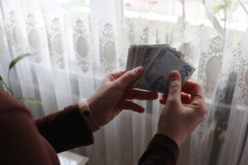 Woman's hand counting one hundred Turkish Lira. Cost of living. Turkish government paper banknotes. Close-up of Turkish national currency known as 