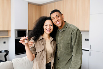 Excited multiracial couple in love move in a new apartment. Cheerful woman in embrace of her guy...