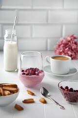 Breakfast with cranberry yogurt with cranberries, cookies, milk and coffee on the kitchen table 
