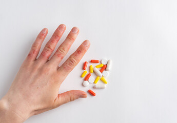 Hand of woman suffering from dermatology disease (eczema, urticaria, allergy, dermatitis, erythema, blistering or infection). Colorful pills. White background, copy space. Medical treatment concept.