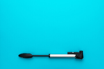 Bicycle pump over turquoise blue background with copy space. Top down flat lay photo of compact bike pump.
