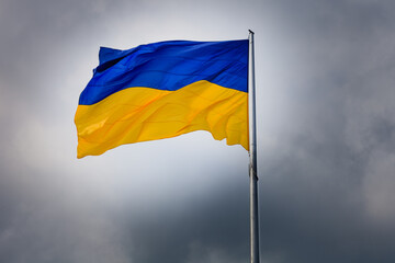 Dnipro. Flagge der Ukraine. Ukraine in der Gefahr.Aggression gegen die Ukraine. Flagge als Symbol des Sieges im Krieg. Schwarze Wolken über der ukrainischen Flagge.