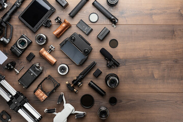 Short movie production essentials on wooden background with copy space. Different video making equipment for indie cinema production. Video production tools on brown table view from above.