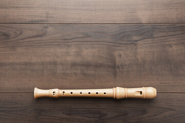 Overhead photo of block flute with copy space. Flat lay top-down composition of wooden recorder on the wooden background. - obrazy, fototapety, plakaty