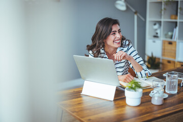 Pretty pretty lady with black hair working at laptop sitting at a table at home - check out online stores selling cyber mondays - tech woman concept for alternative freelance office