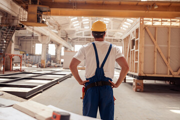 Male builder in safety helmet observing building under construction