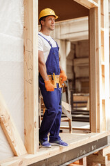 Male builder in work overalls standing in construction cabin