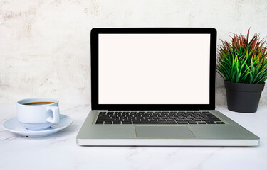 Laptop or notebook with blank screen, coffee and potted plant on white table.