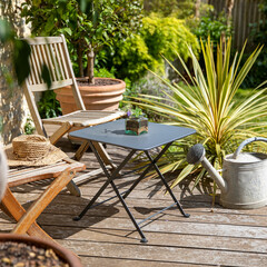 Salon de jardin sur une terrasse en bois avec chaise et table d'apéro.