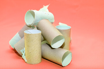 A pile of empty toilet paper tubes on a red background. The concept is a global crisis and a lack of things to meet basic needs.