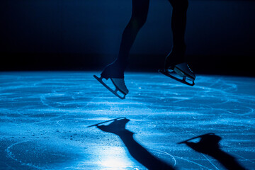 The female athlete in figure skating at the moment of the jump. Women's legs in white skates for...