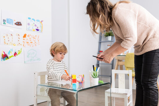 Psychologist near boy drawing on paper