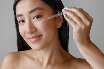 Young woman applying vitamin serum on her face