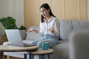 Beautiful young woman making video conference call via computer at home , business technology concept