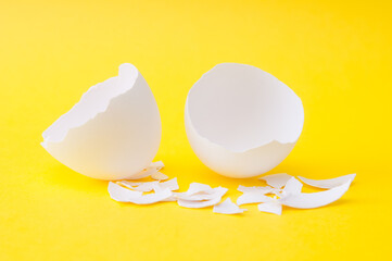 Cracked white egg shell close up on yellow background