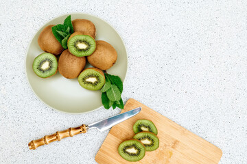 Fresh juice kiwi and green mint leaves in green plate on the table. Sliced ripe exotic fruits. Top view. Space for text.
