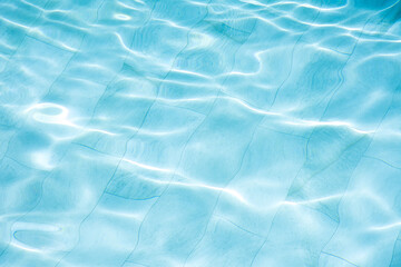 Water in marble swimming pool rippled with sunny reflections background.