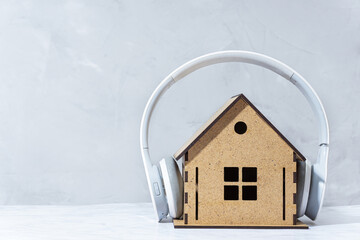 White wireless headphones on a toy wooden house